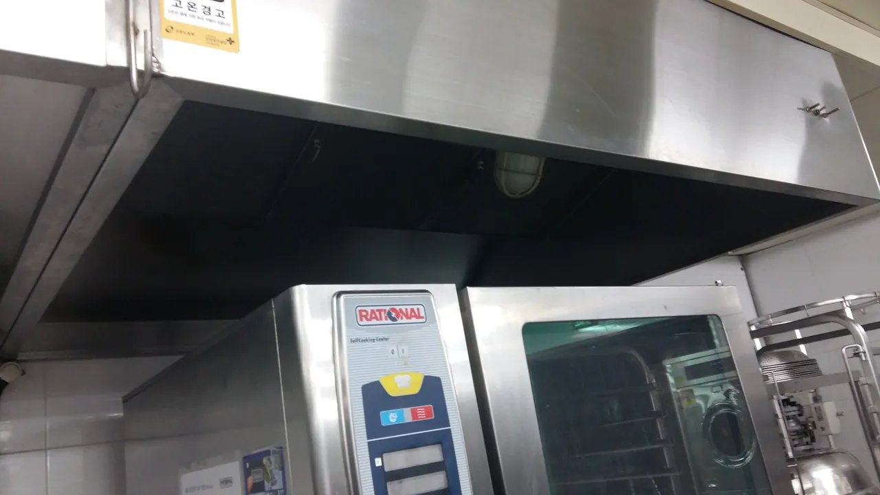 후드 아래 콤비오븐이 놓인 주방 — 웨딩홀후드청소